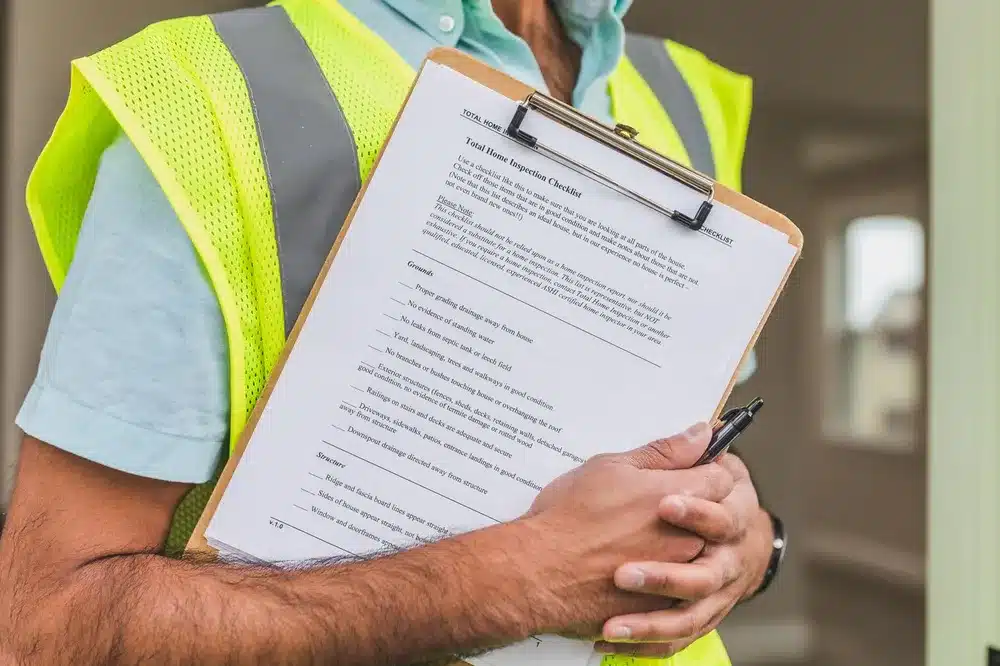 Homme en gilet de sécurité jaune tenant contre lui un porte-bloc avec une liste de contrôle imprimée en anglais